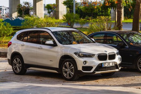 Photo for Side, Turkey -January 21, 2023:   white  BMW X-1  is parked  on the street in city against the backdrop of a buildung, garden - Royalty Free Image