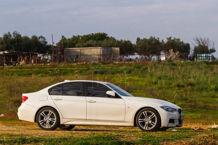 Foto de Side, Turkey -January 21, 2023: el BMW 3-series blanco está estacionado en el villo contra el telón de fondo de un jardín - Imagen libre de derechos