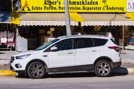 Photo for Side, Turkey -January 23, 2023:   white Ford Kuga   is parked  on the street on a warm  day against the backdrop of a house , shops - Royalty Free Image