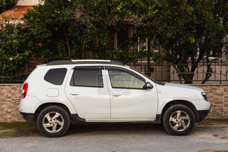 Téléchargez les photos : Side, Turkey  February 13 2022:    white  Dacia Daster    is parked  on the street on a warm summer day against the backdrop of a buildung, trees - en image libre de droit