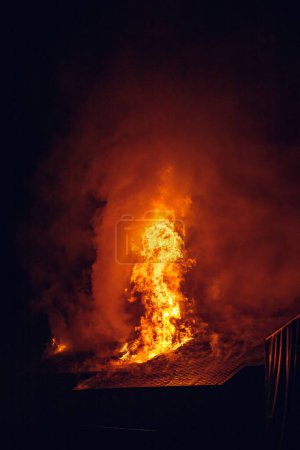 Foto de Casa en llamas por la noche. Fuerte fuego en un pequeño pueblo - Imagen libre de derechos
