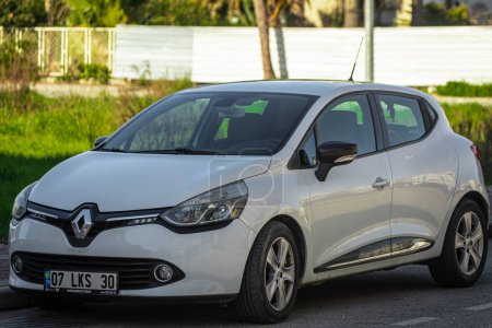 Foto de Lado; Turquía 05 de febrero 2023: Renault Clio blanco está estacionado en la calle en un cálido día de verano con el telón de fondo de un parque - Imagen libre de derechos