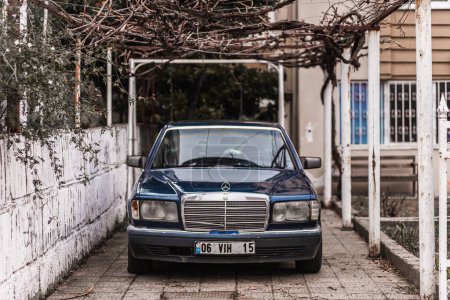 Foto de Side, Turkey 09 de febrero de 2023: Mercedes-Benz W124 negro está estacionado en la calle en un día cálido con el telón de fondo de un edificio. Fotografía de un coche clásico en una calle de Turquía - Imagen libre de derechos