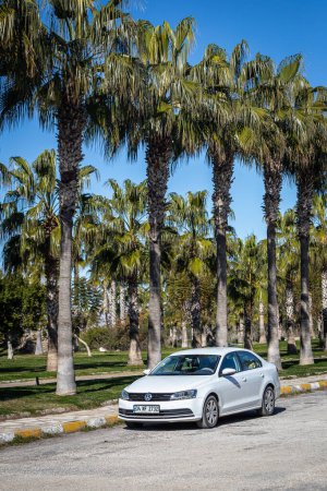 Photo for Side; Turkey  February 09 2023:   white Volkswagen Passat   is parked  on the street on a warm    day against the backdrop of a park, palms - Royalty Free Image