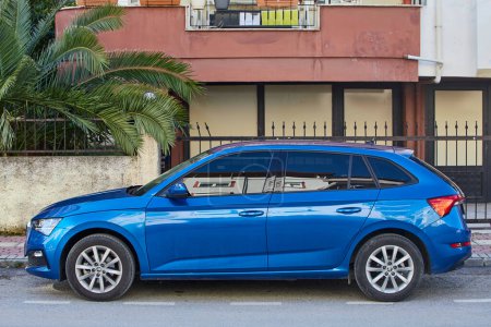 Photo for Side, Turkey - February 11, 2023:  blue Skoda Kamiq   is parking  on the street on a warm autumn day against the backdrop of a  city - Royalty Free Image