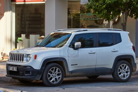 Photo for Side, Turkey  February 11 2023:      white Jeep Renegade   is parking  on the street on a  warm  day against the backdrop of a  fence, garden - Royalty Free Image