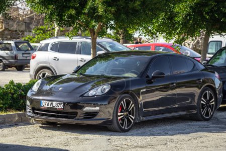 Photo for Side, Turkey  February 09 2023:   black Porsche Panamera     is parked  on the street on a warm  autumn  day against the backdrop of a  parking - Royalty Free Image