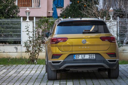 Foto de Side, Turkey - 13 de febrero de 2023: amarillo Volkswagen T-Roc está estacionado en la calle en un día cálido con el telón de fondo de un edificio, tiendas - Imagen libre de derechos