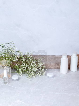 Téléchargez les photos : Ensemble de produits minimaliste et élégant pour soins du corps et du visage et accessoires de bain avec des fleurs blanches sèches dans un intérieur léger et doux - en image libre de droit