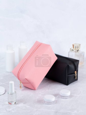 Photo for Colorful  cosmetic bags  on a stone table, with flowers and perfume in the background - Royalty Free Image