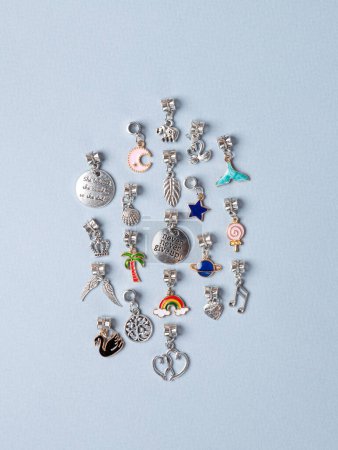 Photo for A variety of metal charms for a child's necklace or bracelet. Many charms isolated on a white background: planet , star,  seashell, tree,  crown , lekki, etc. - Royalty Free Image