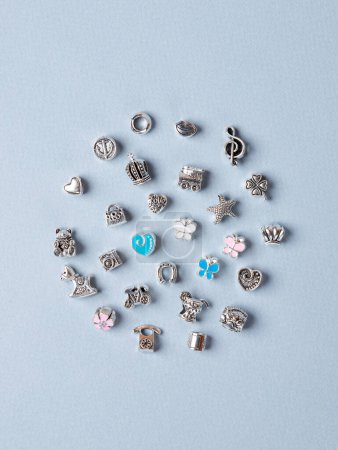 Photo for A variety of metal charms for a child's necklace or bracelet. Many charms isolated on a white background: star ,  flower,  lips, tree, cactus, lekki, etc. - Royalty Free Image