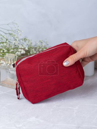 Photo for Close up of hands of unrecognisable woman taking make-up products from her red cosmetic bag. - Royalty Free Image