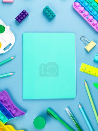 Foto de Cuaderno y bolígrafos, lápices, clips y otros artículos de oficina sobre fondo azul - Imagen libre de derechos