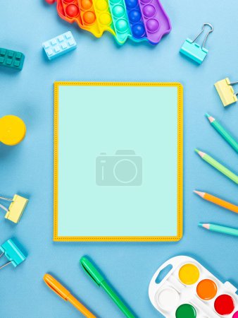 Photo for Close-up of a paper notebook with blank sheets, a pen, a pencil and a paper clip on a blue background - Royalty Free Image