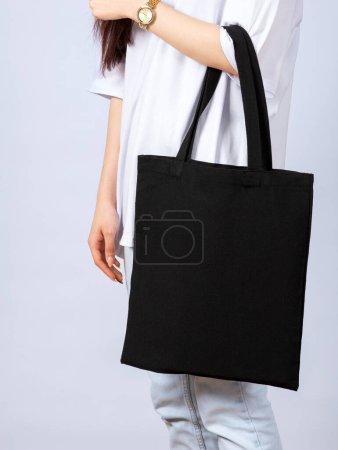 Téléchargez les photos : Jeune femme avec des sacs en coton noir dans ses mains. - en image libre de droit