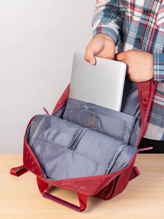 Photo for A man is packing his laptop into a backpack, close-up - Royalty Free Image