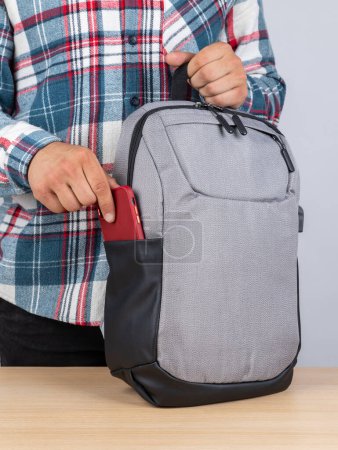 Photo for Close-up of a young male student taking out a phone from his backpack. - Royalty Free Image