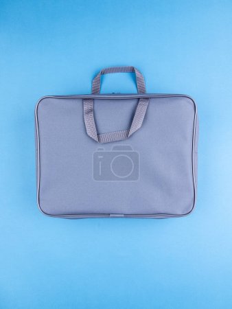 Foto de Carpeta de maletín gris para documentos y artículos escolares en una mesa azul brillante junto a papelería - Imagen libre de derechos