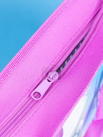 Photo for Close-up of a zipper on a pink school pencil case on a blue background. Back to school. copy space - Royalty Free Image