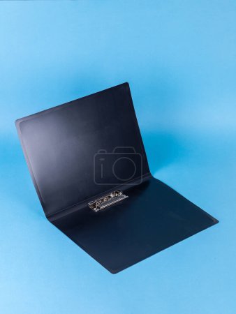 Foto de Carpeta de plástico negro para documentos aislados sobre fondo azul - Imagen libre de derechos