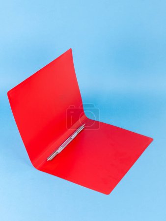 Foto de Carpeta de plástico rojo para documentos aislados sobre fondo azul - Imagen libre de derechos
