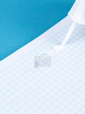 Photo for A hand holds a black corrective brush to remove excess tape information on the table. - Royalty Free Image