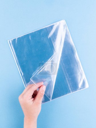 Foto de Primer plano de las cubiertas transparentes para un libro de texto y un cuaderno sobre un fondo azul - Imagen libre de derechos