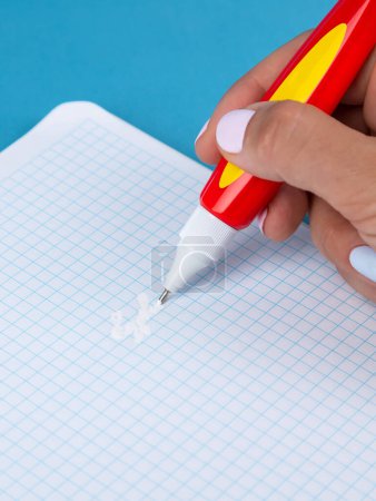 Photo for A hand holds a black corrective pencil to remove excess tape information on the table. - Royalty Free Image