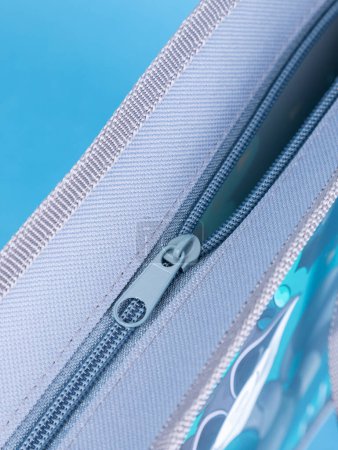 Photo for Close-up of a zipper on a gray school pencil case on a blue background. Back to school. copy space - Royalty Free Image