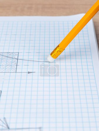 Photo for Close-up woman erasing a graph with a white  rubber band on a slate pencil in a checkered notebook - Royalty Free Image