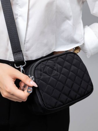 Photo for Close-up of a woman in a stylish black skirt. and a white shirt zips up a little black bag - Royalty Free Image