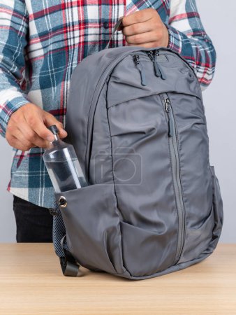 Photo for Close-up of a young male student taking out a bottle of water from his backpack. - Royalty Free Image