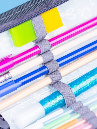 Téléchargez les photos : Gros plan des fournitures scolaires dans un étui à crayons sur fond bleu avec chemin de coupe - en image libre de droit