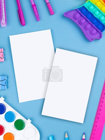 Foto de Diseño plano de bloc de notas en blanco con pluma, acuarela, pop it y pegatinas sobre fondo colorido - Imagen libre de derechos