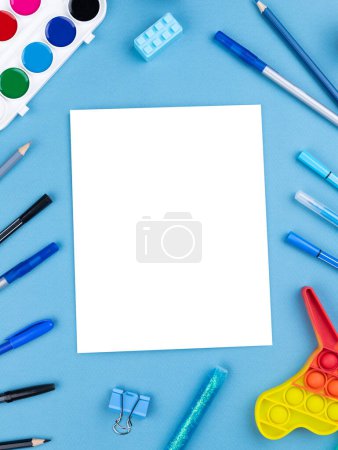 Foto de Espacio de trabajo infantil transparente, cuaderno de bocetos, pluma, pop it, lápiz, cactus, caucho sobre fondo azul para espacio de copia. - Imagen libre de derechos
