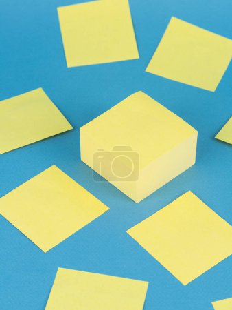 Téléchargez les photos : Feuilles de papier autocollant vierges jaunes, isolées sur fond bleu - en image libre de droit