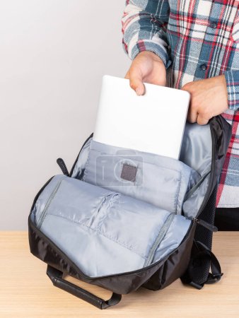 Téléchargez les photos : Gros plan d'un jeune étudiant qui sort un ordinateur portable d'un sac à dos. - en image libre de droit
