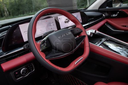 Foto de Novosibirsk, Rusia - 29 de agosto de 2023: automóvil negro EXEED RX, rojo y negro Interior: volante, palanca de cambios y tablero de instrumentos, control de temperatura, velocímetro, pantalla. Salón de una nueva ca con estilo - Imagen libre de derechos