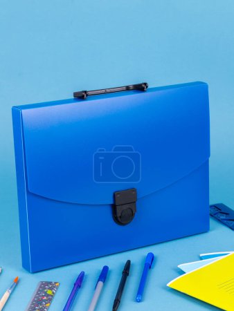 Téléchargez les photos : Porte-documents en plastique bleu pour documents et articles scolaires sur une table bleu vif - en image libre de droit