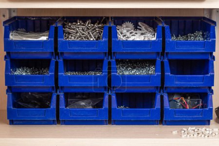 Photo for Blue box with small construction objects. Many storage compartments are filled with construction supplies containing screws, nuts, bolts, nails and other workshop tools. - Royalty Free Image