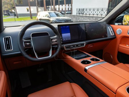 Téléchargez les photos : Intérieur de la voiture - volant et tableau de bord, indicateur de vitesse, affichage dans une voiture neuve avec sièges en cuir orange - en image libre de droit