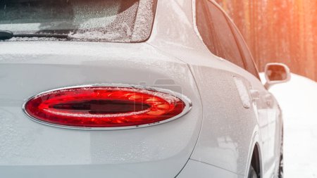 Téléchargez les photos : Détail rapproché sur l'un des feux arrière rouges LED voiture multisegment blanc moderne avec neige. Détail extérieur automobile - en image libre de droit