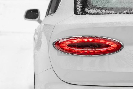 Foto de Detalle de cerca en uno de los led rojo luz trasera moderno coche crossover blanco con nieve. Detalle exterior automóvil - Imagen libre de derechos