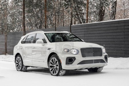 Photo for Novosibirsk, Russia -  November 03  , 2023:  white Bentley Bentayga  parked on the street on a winter day against the backdrop of   building , front  view - Royalty Free Image