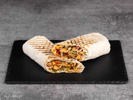 Téléchargez les photos : Rouleau shawarma dans la lavande avec poulet, légumes frais, sauce teriyaki et frites sur un fond en bois. Concentration sélective - en image libre de droit