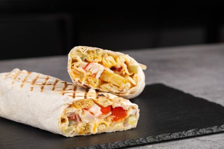 Photo for Shawarma roll in lavash with crab sticks, fresh vegetables, cream sauce and french fries on a wooden background. Selective focus - Royalty Free Image