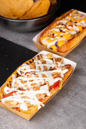 Foto de Una cadena de deliciosos hot dogs de diferentes recetas en góndolas de papel - Imagen libre de derechos