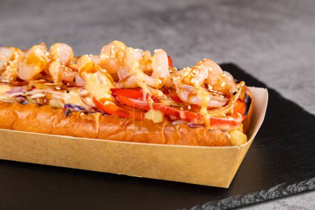 Téléchargez les photos : Hot-dogs grillés gastronomiques aux crevettes, sauce et poivrons, oignons et frittes.Hot-dogs savoureux frais - en image libre de droit