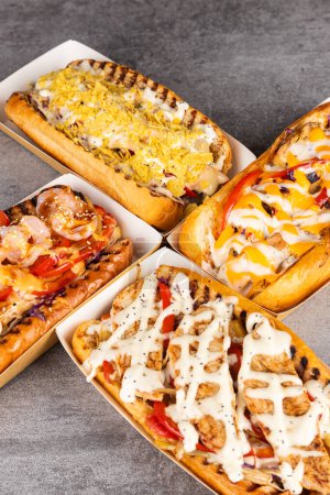 Téléchargez les photos : Hot dog grillé barbecue avec saucisse et moutarde jaune avec vue sur le ketchup. Restauration rapide américaine traditionnelle. - en image libre de droit